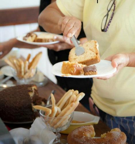 a person holding a plate with a piece of cake and french fries at Pousada Maracabana Spa in Porto De Galinhas