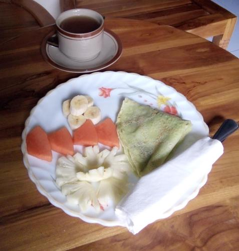 Un plato de comida en una mesa con una taza de café. en Indraprastha 2 Bungalow, en Ubud