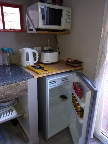 a small kitchen with an open refrigerator and a microwave at El Tamarisco in Puerto Pirámides
