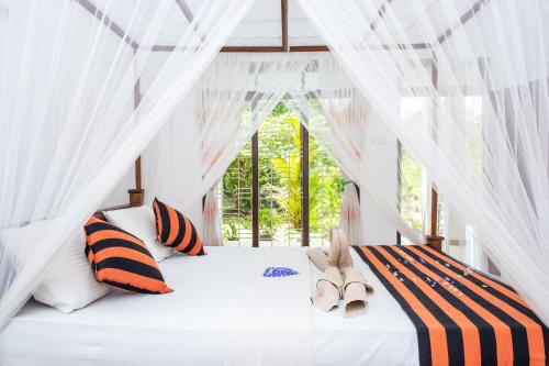 a bedroom with a white canopy bed with orange and black pillows at Sigiriya Sun Shine Villa in Sigiriya