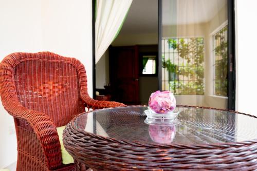 a glass table with a pink flower in a glass jar at Riviera Punta Cana Eco Travelers in Punta Cana