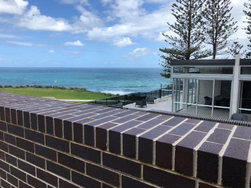 a house with a brick wall and the ocean at Headlands Austinmer Beach in Austinmer