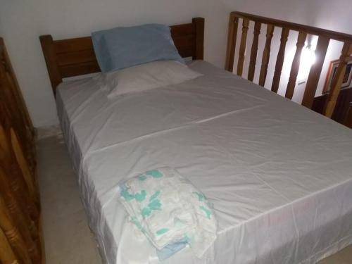 1 cama con sábanas blancas y almohada azul en Cabaña Coveñas Punta Bolivar, en Coveñas