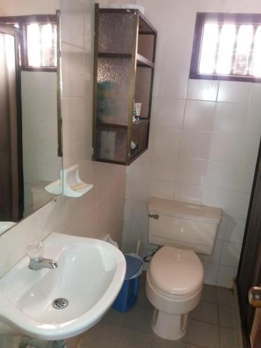 a white bathroom with a toilet and a sink at Cabaña Coveñas Punta Bolivar in Coveñas