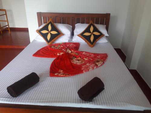 a bed with a red dress and two pillows on it at adam's apple homestay in Ella