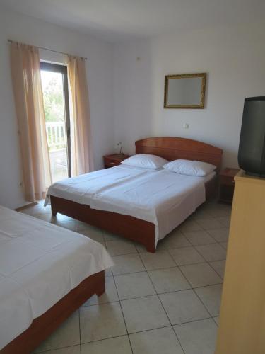 a bedroom with two beds and a tv and a window at Apartments Galic Omis in Omiš
