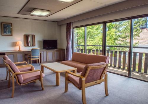 a living room with a couch and chairs and a balcony at Hotel Laforet Shuzenji in Izu