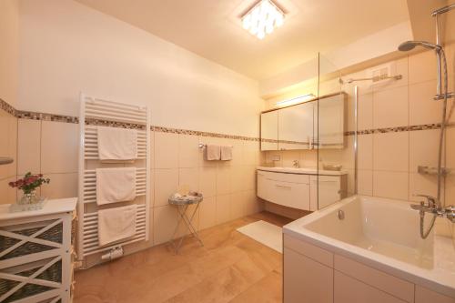 een badkamer met een bad, een wastafel en een spiegel bij Appartement Auszeit in Saalfelden am Steinernen Meer
