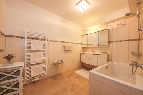 a bathroom with a tub and a sink and a mirror at Appartement Auszeit in Saalfelden am Steinernen Meer