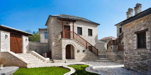 an old stone house with a staircase and grass at Gioraldi Art Hotel in Ano Pedina