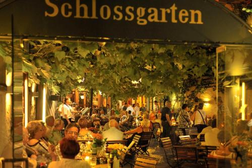 a group of people sitting at tables outside a restaurant at Breuer's Rüdesheimer Schloss in Rüdesheim am Rhein