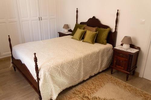 a bedroom with a large bed with green pillows at A Casa da Avó Ana in Arneiro das Milhariças