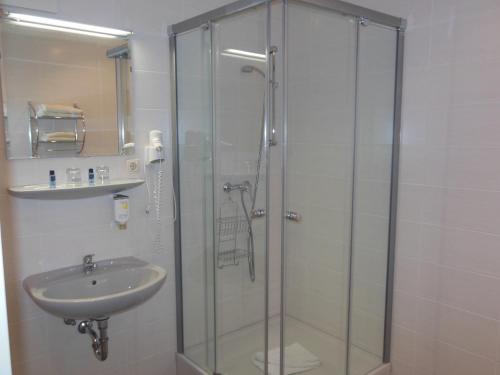 ein Bad mit einer Glasdusche und einem Waschbecken in der Unterkunft Hotel Asterra in Saalfeld