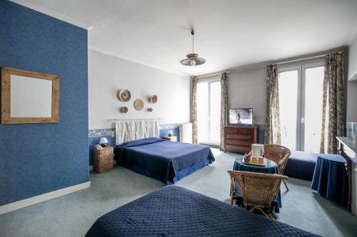 a blue bedroom with two beds and a table at Hôtel Central in Pau