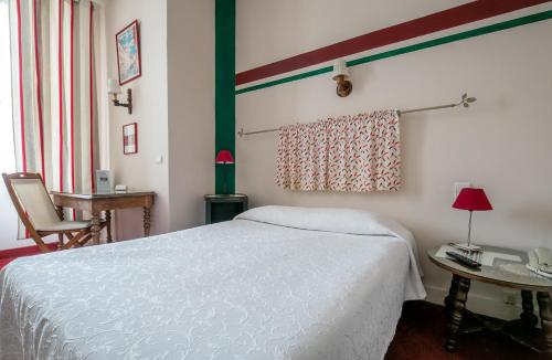a bedroom with a white bed and a table at Hôtel Central in Pau