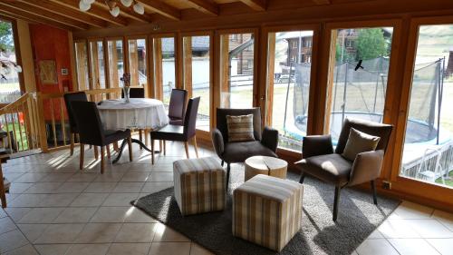 een eetkamer met een tafel, stoelen en ramen bij Hotel Grimsel in Obergesteln