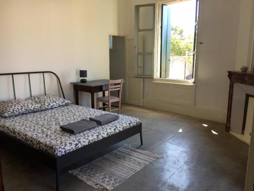 Schlafzimmer mit einem Bett, einem Tisch und einem Fenster in der Unterkunft Le cœur d'Orques in Saint-Georges-dʼOrques