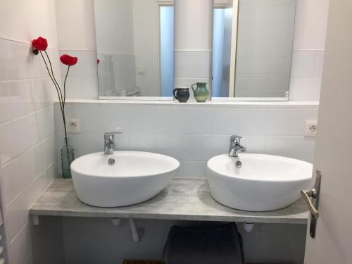 a bathroom with two sinks and a vase with a red rose at Le cœur d'Orques in Saint-Georges-dʼOrques