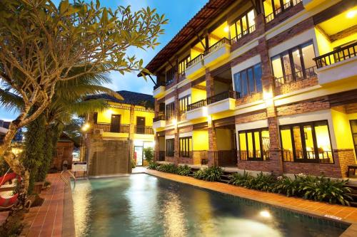 a hotel with a swimming pool in front of a building at Khaolak Tony Lodge in Khao Lak