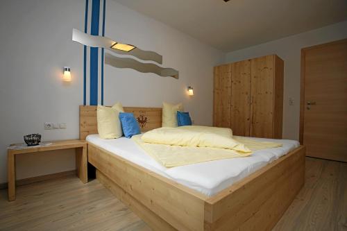 Un dormitorio con una gran cama de madera con almohadas azules en Apart Knabl, en Sankt Leonhard im Pitztal