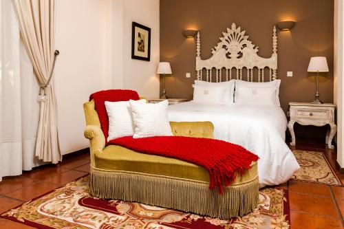 a bedroom with a large bed with a red blanket on a chair at Quinta do Covanco in Alenquer