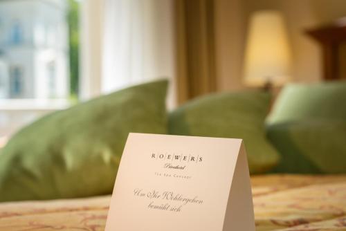 a sign on a bed with a green couch at ROEWERS Privathotel & Spa in Ostseebad Sellin