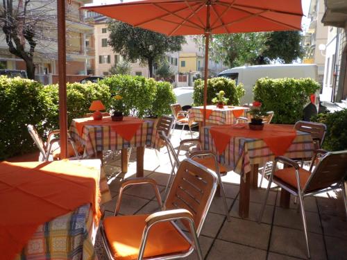 an outdoor patio with tables and chairs and an umbrella at Hotel Paolina in Viareggio