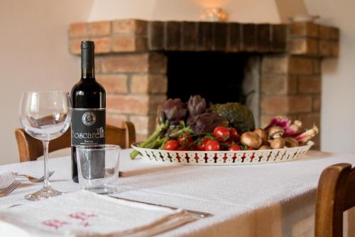 a table with a bottle of wine and a bowl of vegetables at Agriturismo Pometti - Fattoria La Selva in Trequanda