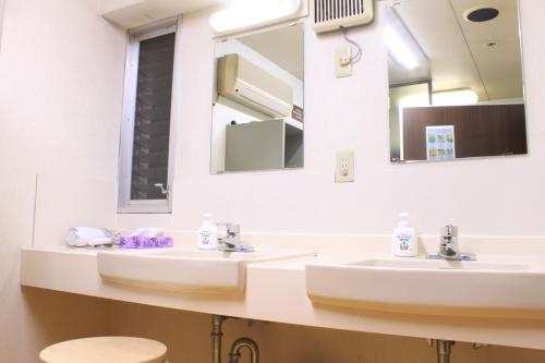 a bathroom with two sinks and two mirrors at T and K Hostel Kobe Sannomiya East in Kobe