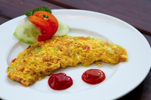 ein weißer Teller mit einem Omelett und Gemüse darauf in der Unterkunft Pondok Ayu shanti in Ubud