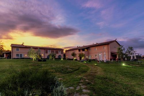 a house in a field with a sunset in the background at Le Sodole Country Resort & Golf in Pontedera