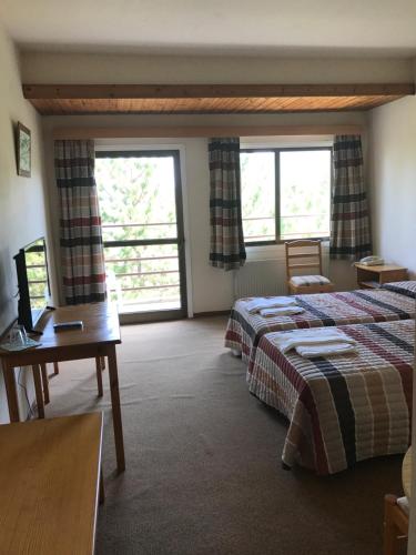 a room with two beds and a table and two windows at Health Habitat Hotel & Slimming Resort in Pedoulas
