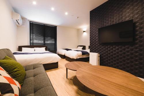 a hotel room with two beds and a flat screen tv at Trip Base HAKATAEKIMAE in Fukuoka