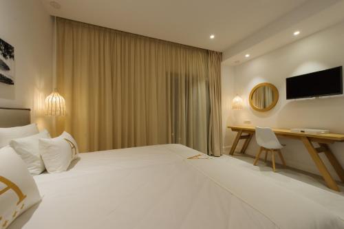 a hotel room with a large white bed and a desk at Alfa Hotel in Parga