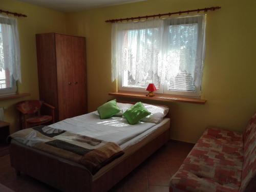 Un dormitorio con una cama con almohadas verdes y una ventana en Dom Wczasowy Mateusz, en Rewal