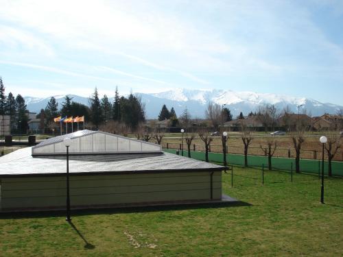 a building in a field with mountains in the background at Apartamentos Monte Hernanz in Riaza