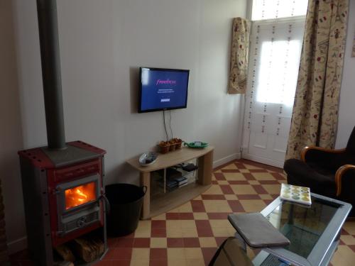 a living room with a wood stove and a tv at maison floréal in Criel-sur-Mer