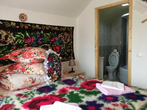 a bedroom with a bed with a floral headboard and a toilet at Sub Creasta Cocosului in Breb