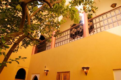 a yellow building with a balcony and a tree at Ryad El Borj in Marrakech