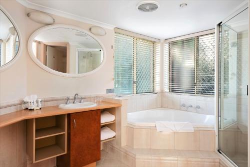 een badkamer met een bad, een wastafel en een spiegel bij Quest Yelverton Kalgoorlie in Kalgoorlie