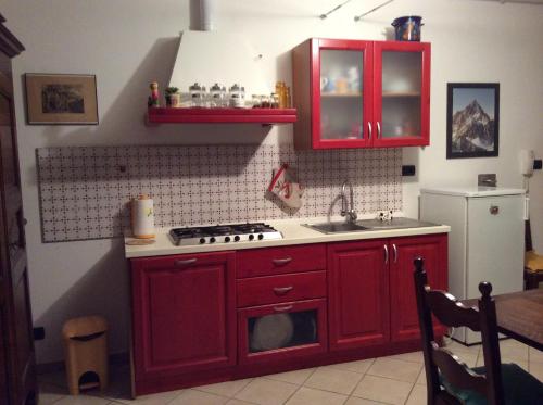 a kitchen with red cabinets and a stove and a sink at I "Giardin" in Crissolo