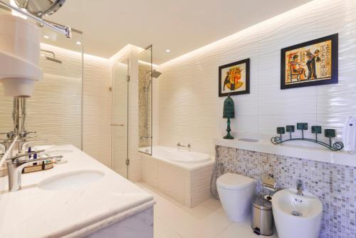 a bathroom with a sink and a tub and a toilet at Royal Central Hotel and Resort The Palm in Dubai