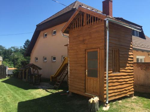 a small wooden cabin with a slide next to a house at Bakonyi Kis-Lak in Bakonykoppány