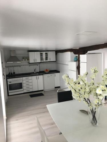 a kitchen with white cabinets and a table with a vase of flowers at Castro Sun And Beach in Castro-Urdiales