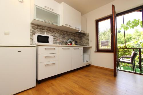 a kitchen with white cabinets and a microwave at Apartment Denza City Center Sarajevo in Sarajevo