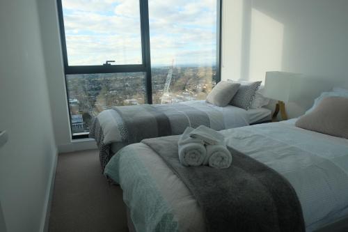 a hotel room with two beds with towels on them at Whitehorse Towers Self Service Holiday Apartment in Box Hill