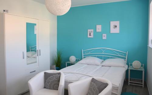 a blue bedroom with a bed and two chairs at Studio Eleven in Kisvárda
