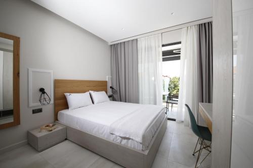 a bedroom with a white bed and a window at Albatros Suites in Nea Vrasna