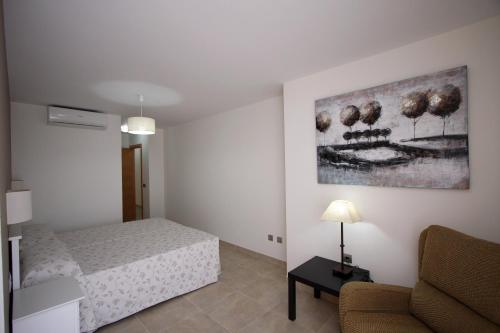 a bedroom with a bed and a couch and a painting at Apartamentos La Botica de Nerja in Nerja