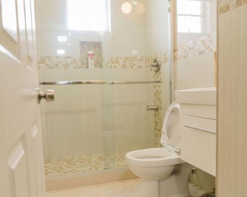 a bathroom with a toilet and a glass shower at Ez Living Apartments in Bridgetown